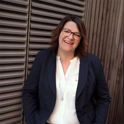 Porträtfoto von Anita Zehrer, Immobilienfachwirtin und Gutachterin, lächelnd vor Holzfassade – persönliche Ansprechpartnerin bei Zehrer Immobilien.